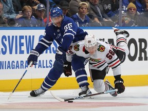 MacKenzie Entwistle of the Chicago Blackhawks battles for the puck against Mark Giordano of the Toronto Maple Leafs.
