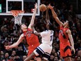 Naz Reid of the Minnesota Timberwolves is blocked at the net by Jakob Poelt and Scottie Barnes of the Toronto Raptors.