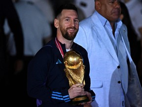 Argentina's captain and forward Lionel Messi holds the FIFA World Cup Trophy.