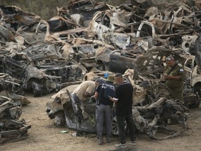 Police officers check cars that were burnt during Hamas' attack on the Israeli south border at a site where police collect damaged and burnt cars from the attacks on October 31, 2023 in Netivot, Israel.