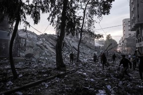 People walk atop the rubble of a tower destroyed in an Israeli air stike in Gaza City on Oct. 7, 2023.