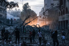 People walk atop the rubble of a tower destroyed in an Israeli air stike in Gaza City on October 7, 2023.