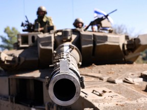 Des soldats israéliens sont assis sur un char Merkava alors qu'ils occupent une position dans un endroit tenu secret à la frontière avec le Liban, le samedi 21 octobre 2023.