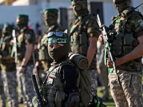 A Palestinian boy carries a toy gun while standing with members of Al-Qassam Brigades, the armed wing of the Hamas movement, during a rally in Gaza City in 2021.