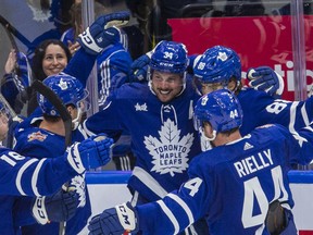 Auston Matthew, surrounded by his team, smiling