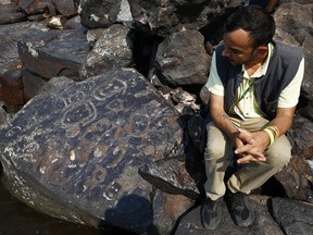 Archaeologist Jaime Oliveira sits next to rock paintings