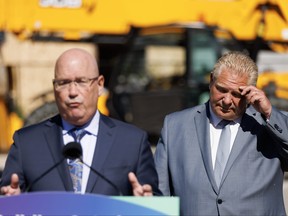 Premier Doug Ford listens as Ontario’s former minister of housing Steve Clark speaks.