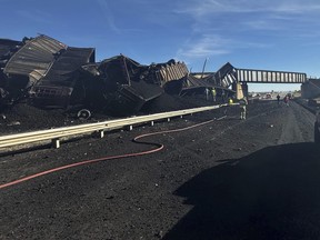 In this photo released by the Pueblo County Sheriff's Office, police respond to the scene of a train derailment near Pueblo, Colo., Sunday, Oct. 15, 2023. The train derailment Sunday spewed coal and mangled train cars across the highway. (Joshua Johnson/Pueblo County Sheriff's Office via AP)