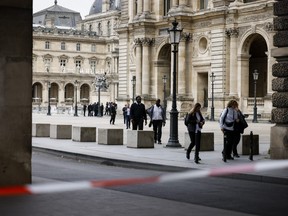 Staff leave the Louvre Museum as people are evacuated after it received a written threat, in Paris, Saturday Oct. 14, 2023.