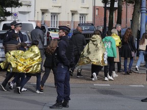 Police officers escort children outside the Gambetta high school during a bomb alert Monday, Oct. 16, 2023 in Arras, northern France.
