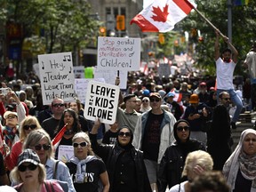 Protesters crowd a street, holding signs