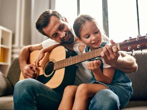 A man teaches a girl to play the guitar