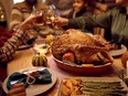 Close up of stuffed turkey during Thanksgiving meal with family toasting in the background.