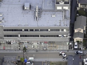 This aerial photo shows first responders take position outside the post office where a man is believed to hole up in Warabi city, Saitama prefecture, north of Tokyo, Tuesday, Oct. 31, 2023.