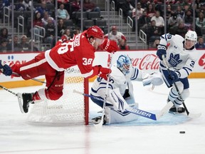 Red Wings right wing Christian Fischer (left) is tripped as Maple Leafs goaltender Joseph Woll and Maple Leafs centre Fraser Minten (right) look on during second period NHL preseason action in Detroit, Saturday, Oct. 7, 2023.