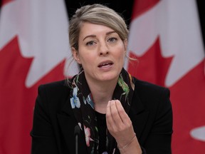 Melanie Joly with Canadian flags behind her