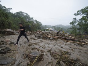 A man crosses a highway blocked by a landslide
