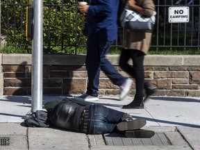 A person sleeps on the sidewalk on Simcoe St.