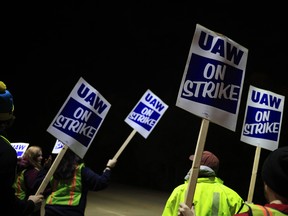 Factory workers and UAW union members form a picket line