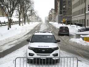 An Ottawa Police officer sits in their cruiser on Wellington Street below Parliament Hill in Ottawa on Friday, Jan. 27, 2023.