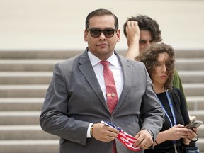 FILE - U.S. Rep. George Santos, R-N.Y., holds a miniature American flag that was presented to him as he departs federal court, June 30, 2023, in Central Islip, N.Y. Santos on Wednesday, Sept. 13, missed another deadline to submit a key financial disclosure report, a months-long delay that the embattled New York Republican blamed on his federal taxes and the desire to avoid a "rushed job."