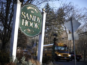 A bus drives past a sign reading Welcome to Sandy Hook