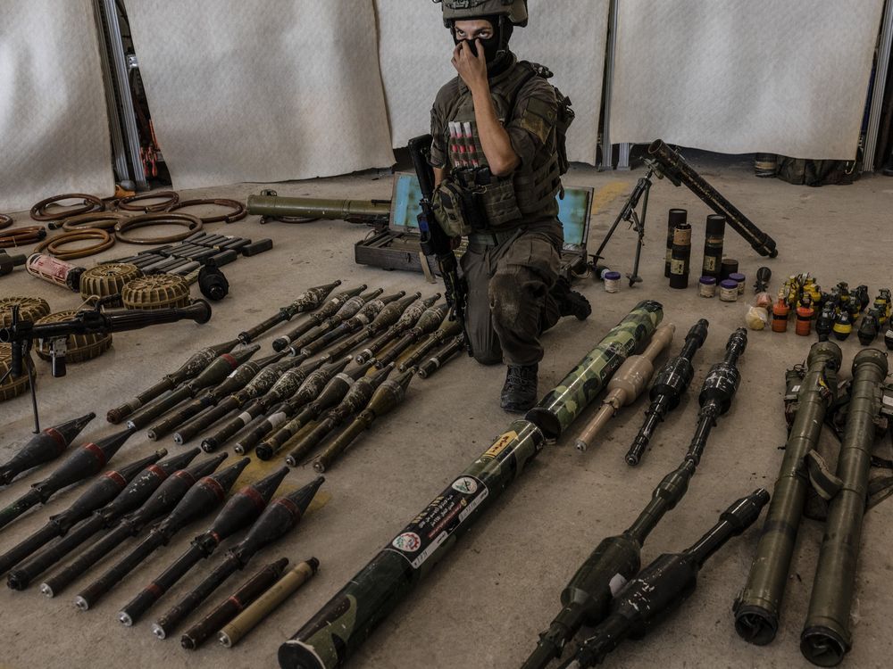 An Israeli officer, identified as Major G. under briefing ground rules, shows a cache of confiscated Hamas weapons at a military base in southern Israel on Oct. 20, 2023. 