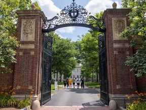 People walk through the gate on Harvard Yard at the Harvard University campus on June 29, 2023 in Cambridge, Mass.