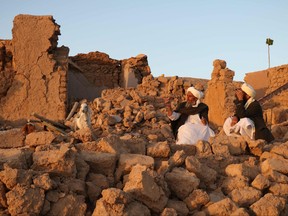 Afghan residents sit at a damaged house after earthquake in Sarbuland village of Zendeh Jan, district of Herat province, on Oct. 7,2023.