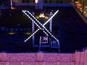 Workers install lighting on an "X" sign
