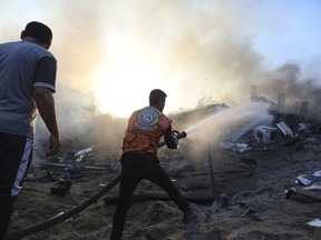 A Palestinian firefighter extinguishes a fire in a destroyed building following Israeli airstrikes on Gaza City