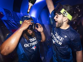 Bo Bichette of the Toronto Blue Jays pours champagne on Vladimir Guerrero Jr.