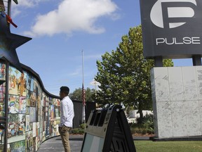 FILE - Brandon Wolf, a survivor of the Pulse nightclub shooting and activist, looks at the photos that are a part of the Pulse memorial in Orlando, Fla., on Sept. 9, 2022. The city of Orlando plans to purchase the gay nightclub property where 49 people were massacred seven years ago, in what at the time was the deadliest mass shooting in modern U.S. history, with the intention of building a memorial for the victims, Mayor Buddy Dyer said Wednesday, Oct. 18, 2023.