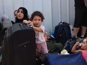 A child cries as people with foreign passports wait at the Rafah gate hoping to cross into Egypt as Israel's attacks on the Gaza Strip continues on Oct. 14, 2023.