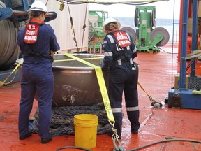 In this photo provided by the U.S. National Transportation Safety Board, U.S. Coast Guard marine safety engineers assigned to the Marine Safety Center in Washington D.C., working for the Marine Board of Investigation for the Titan submersible case, conduct a survey of the aft titanium endcap from the Titan submersible, in the North Atlantic Ocean, Sunday, Oct. 1, 2023. The endcap was recently recovered from the seafloor and successfully transferred to a U.S. port for analysis. (U.S. National Transportation Safety Board via AP)