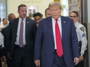 Former U.S. president Donald Trump is surrounded by court officers and secret service agents as he leave the courtroom during a lunch break in his civil business fraud trial, Wednesday, Oct. 4, 2023, in New York.