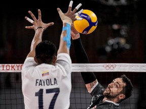 Canada's Stephen Timothy Maar, right, spikes the ball during a men's volleyball preliminary round pool A match between Canada and Venezuela at the 2020 Summer Olympics on July 30, 2021, in Tokyo, Japan.