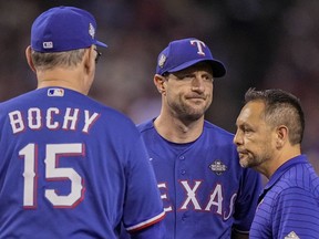 Texas Rangers starting pitcher Max Scherzer leaves the game with head athletic trainer Matt Lucero against the Arizona Diamondbacks during the fourth inning in Game 3 of the baseball World Series Monday, Oct. 30, 2023, in Phoenix.