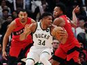 Milwaukee Bucks forward Giannis Antetokounmpo (34) protects the ball as Toronto Raptors' Otto Porter Jr. (left) and Scottie Barnes defend.