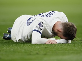 Tottenham's James Maddison lies on the pitch in pain.