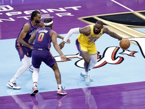LeBron James of the Los Angeles Lakers controls the ball against Jordan Goodwin of the Phoenix Suns.