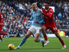 Liverpool defender Trent Alexander-Arnold vies with Manchester City striker Erling Haaland for the ball.