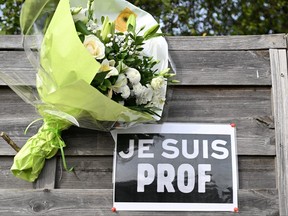 Flowers next to a placard reading "I am a teacher" in tribute to Samuel Paty, the history-geography teacher who was beheaded on Oct. 16, 2020, are pictured near the Bois d'Aulne school in Conflans-Sainte-Honorine, outside Paris, Monday Oct. 16, 2023.