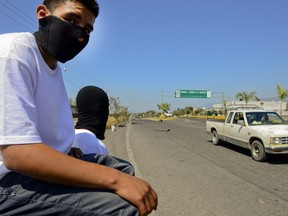In this file photo taken on Feb. 12, 2014, two members of the so-called self-defence groups are pictured at the entrance of Apatzingan community, Michoacan state, Mexico. The vigilante groups are fighting drug cartels.