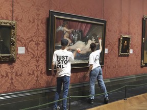 In this photo provided by Just Stop Oil on Monday, Nov. 6, 2023, activists hit the protective glass on a painting at the National Portrait Gallery in London.