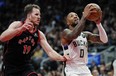 Milwaukee Bucks' Damian Lillard (0) drives past Toronto Raptors' Jakob Poeltl (19) during first half NBA basketball action in Toronto on Wednesday, Nov. 15, 2023.