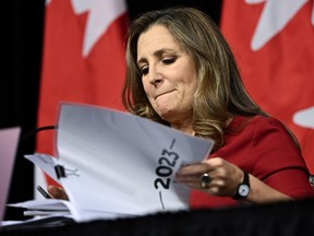 Chrystia Freeland at a table looking down lifting papers