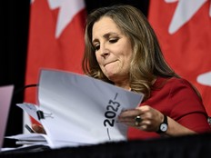 Chrystia Freeland at a table looking down lifting papers