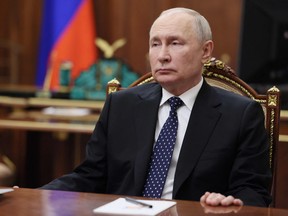 Vladimir Putin sits at a table
