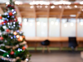Blurred abstract of decorated Christmas tree with toys, gift box and bauble inside office building.